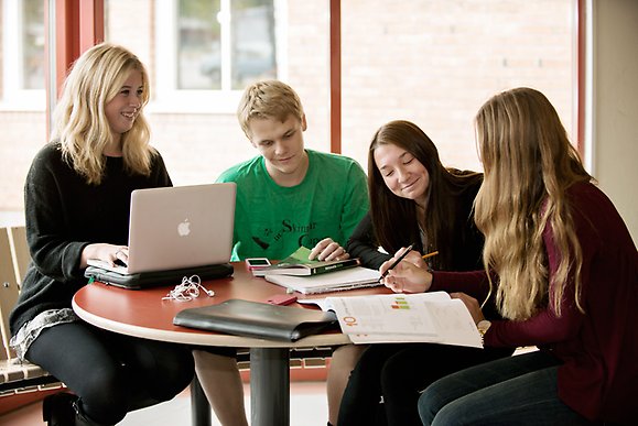 Elever med datorer sitter runt ett bord