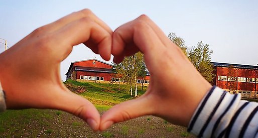Ungärde skola som syns genom ett hjärta bildat av två händer.